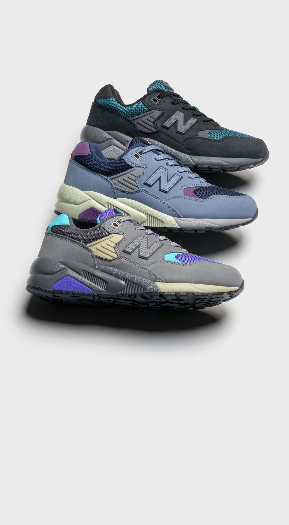 3 New Balance 580 shoes posed in a line against a grey studio background showcasing the color options available 
