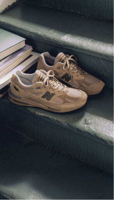 A pair of New Balance Made in UK sneakers on a staircase next to a pile of books.