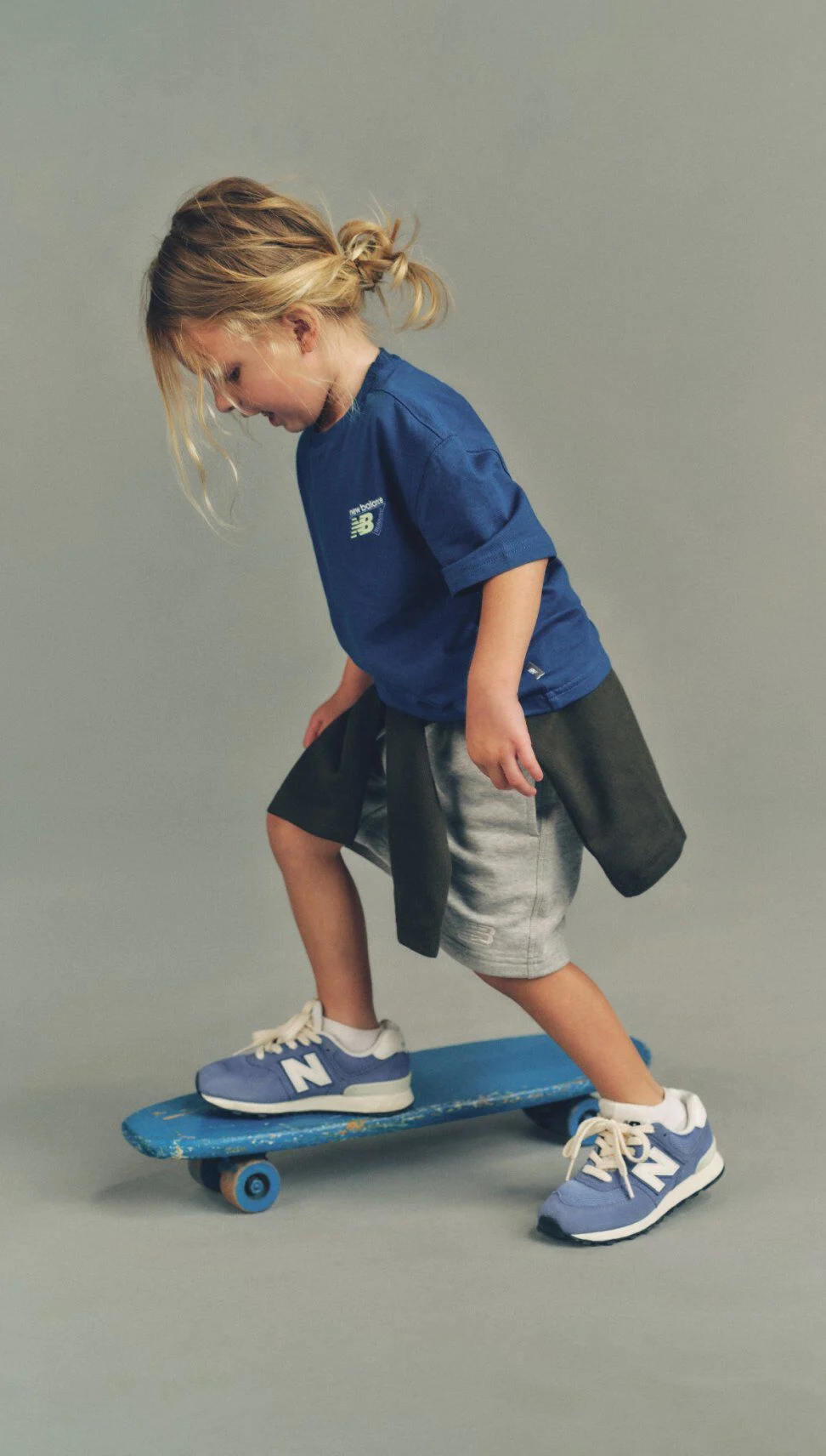 Young girl in a navy tshirt riding a skateboard.