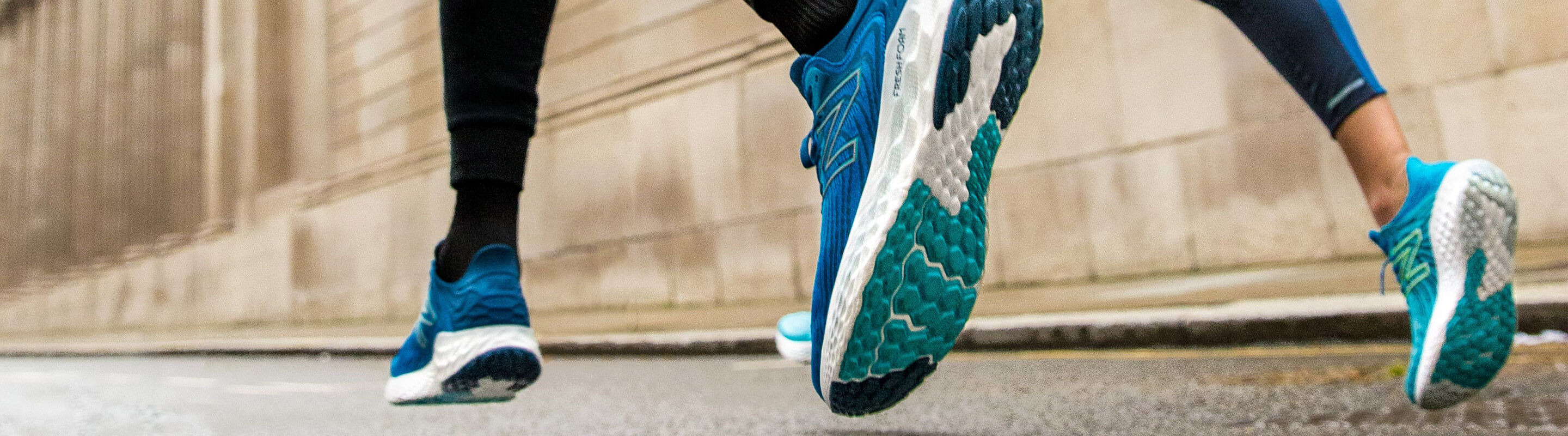 Male and female running on the sidewalk focusing on the shoes in motion.