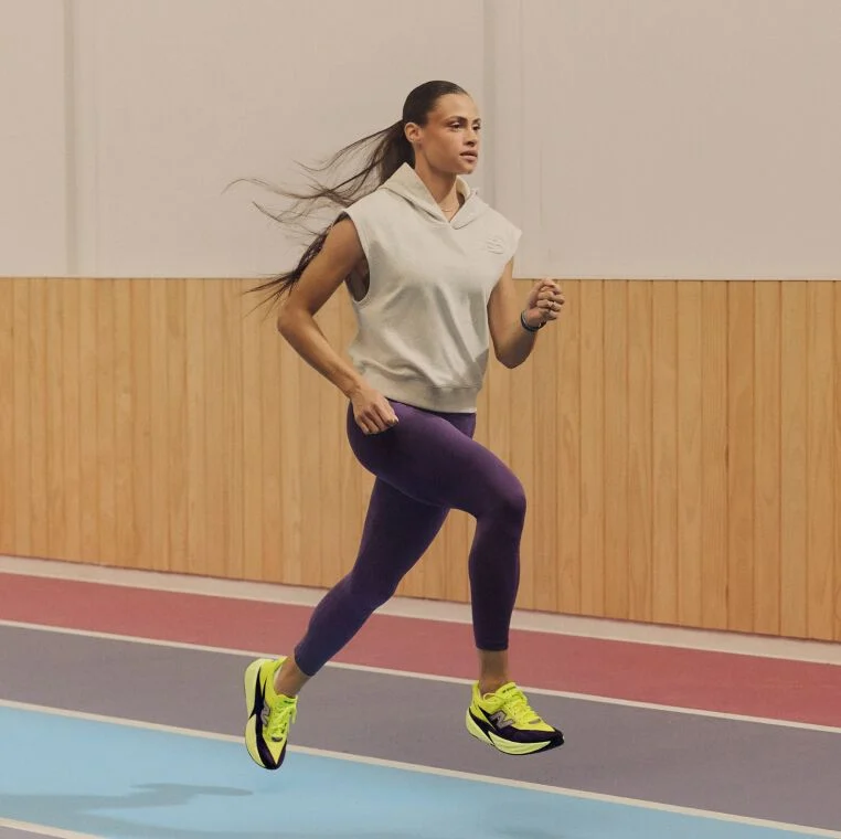 Woman wearing purple pants running on a track
