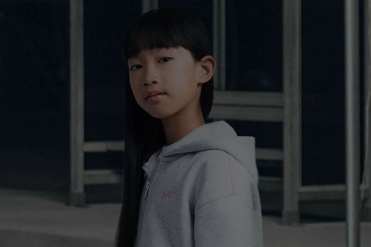 Fille portant un sweat &agrave; capuche gris New Balance