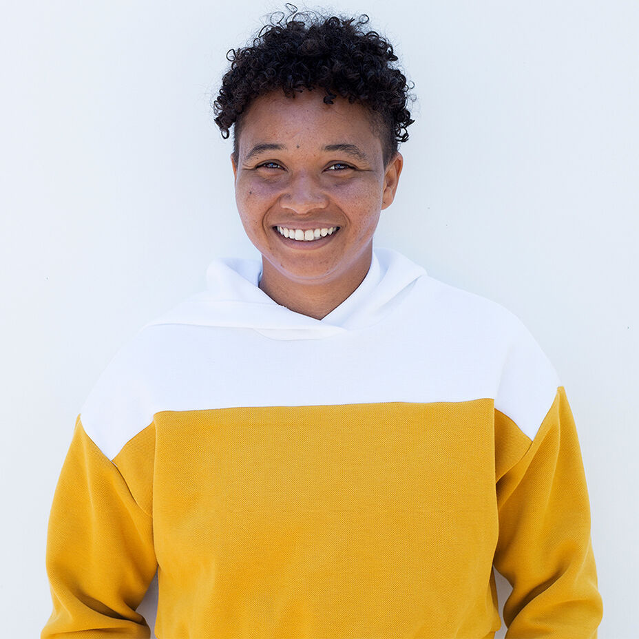 Skateboarder Sammaria Brevard smiling in a white and yellow hoodie