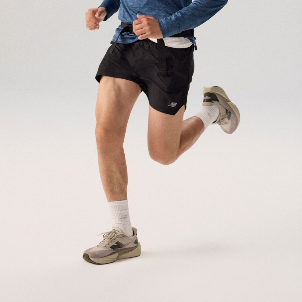 Young man running wearing a navy jacket on a grey background.