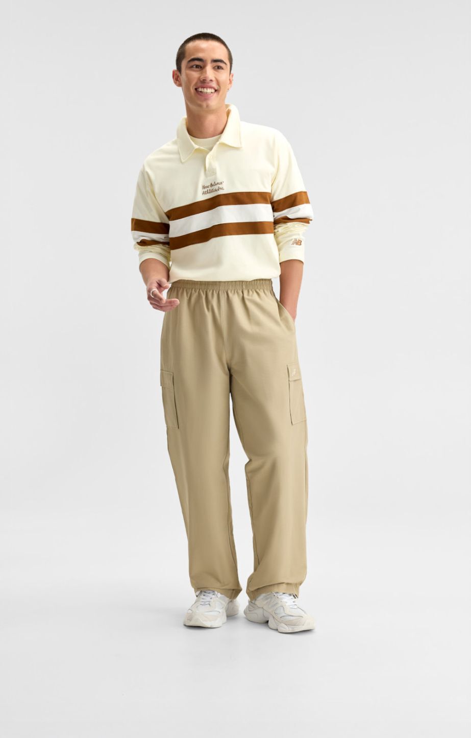 Un homme portant des v&ecirc;tements New Balance cr&egrave;me et brun sur un fond blanc.