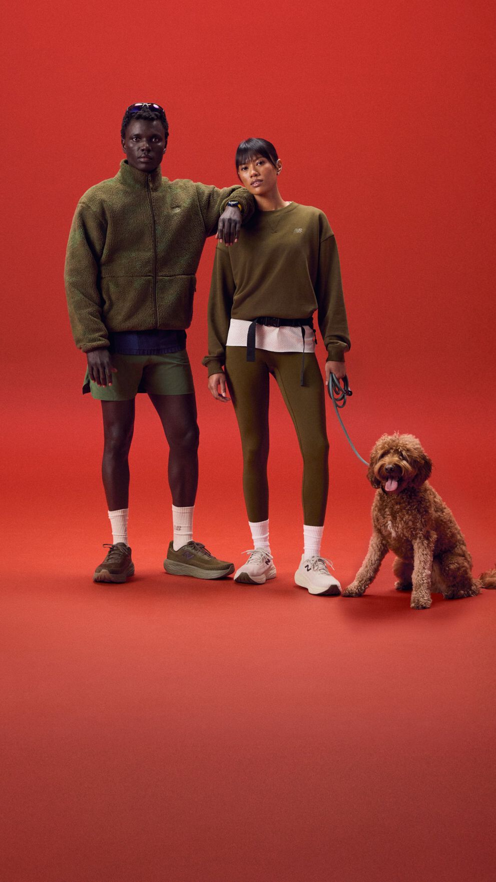 Young couple standing on a red background with a dog.