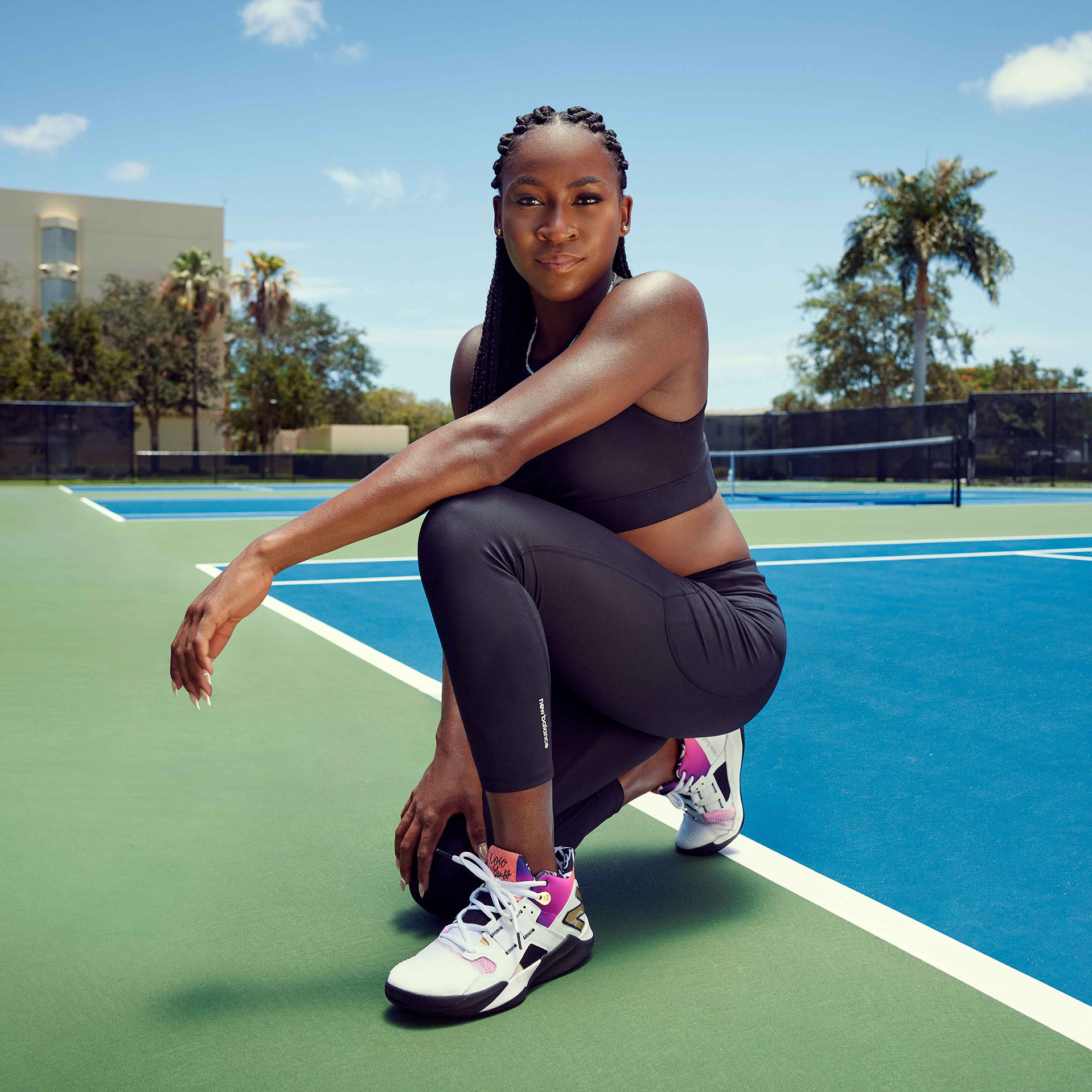 Coco posant sur un genou sur le terrain de tennis.