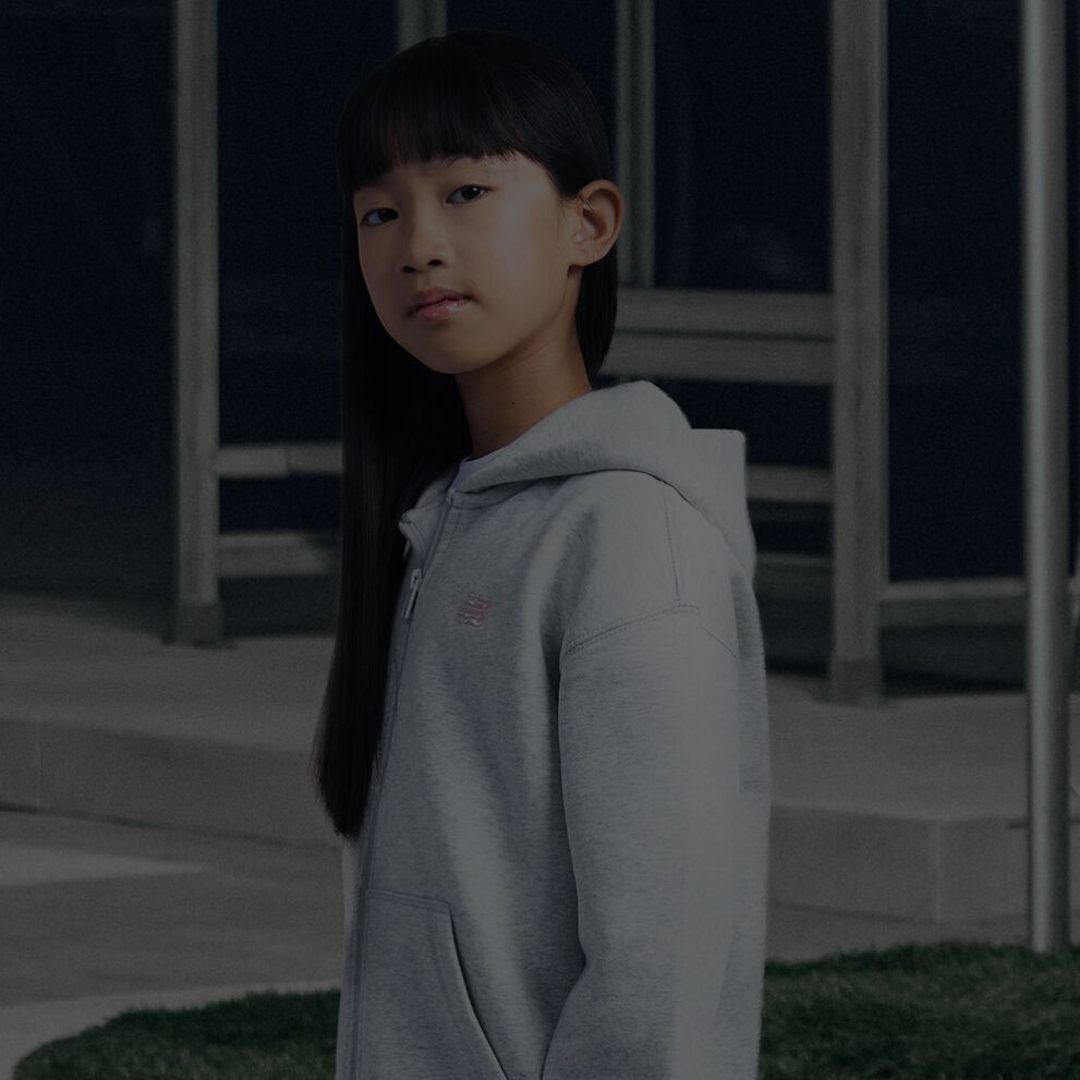 Fille portant un sweat &agrave; capuche gris New Balance