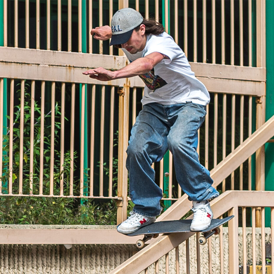 Skateboarder Charlie Birch doing a boardslide down a metal handrail in white and red Numeric shoes