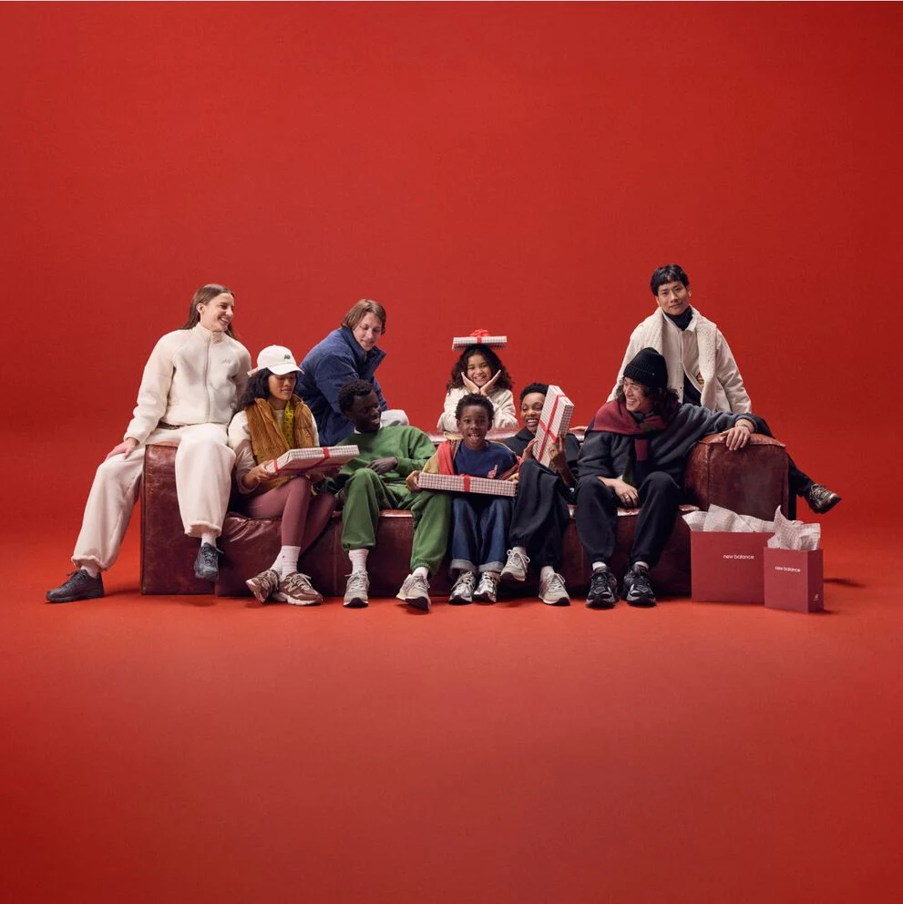 Young family sitting on a red couch holding gifts.