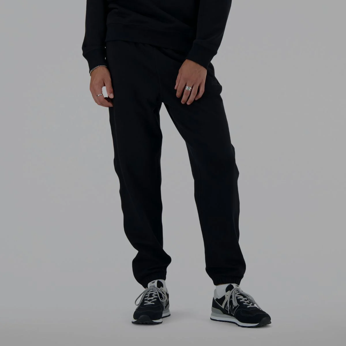 Un homme portant un pantalon de survêtement noir New Balance.