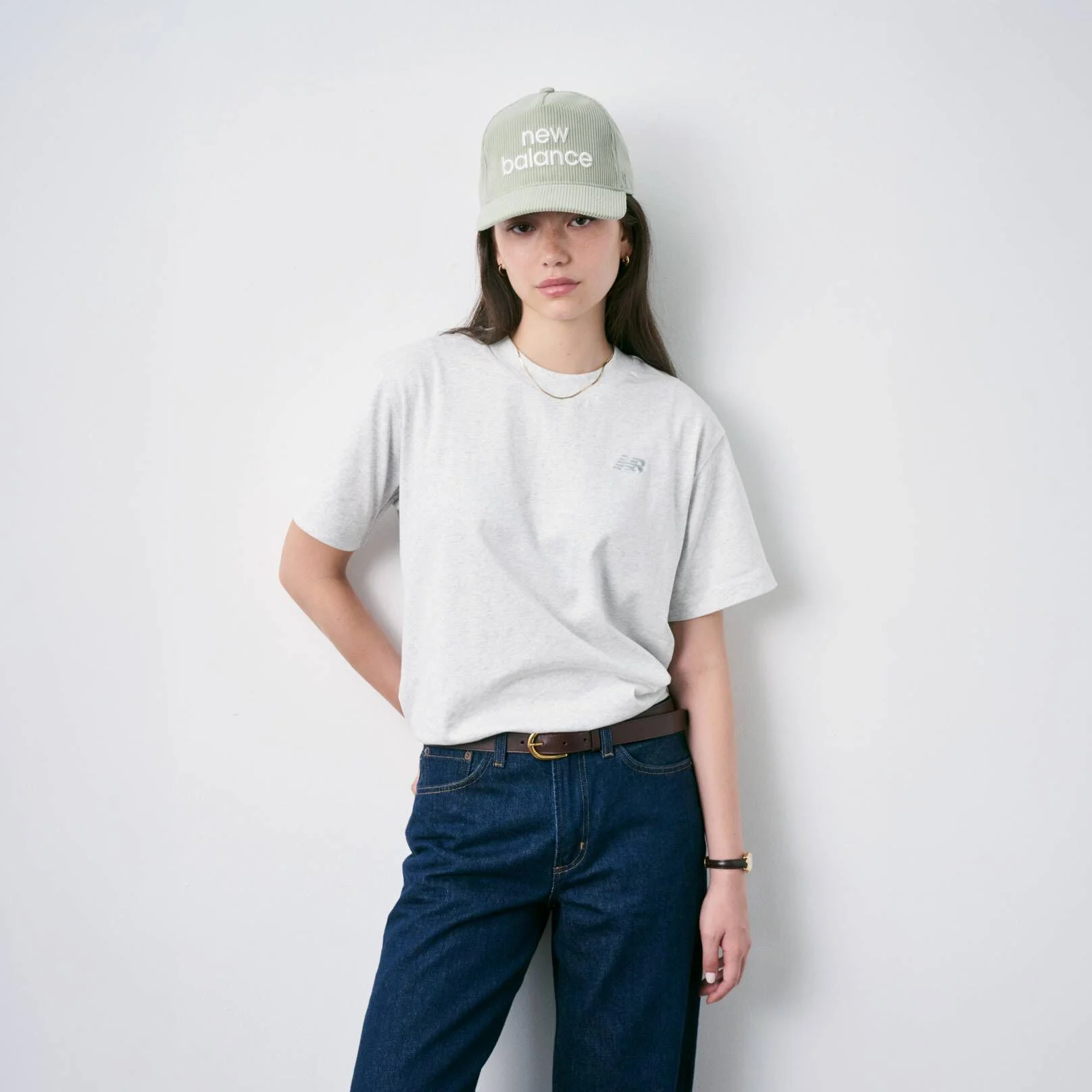 Femme assise par terre, chauss&eacute;e de New Balance et portant une casquette