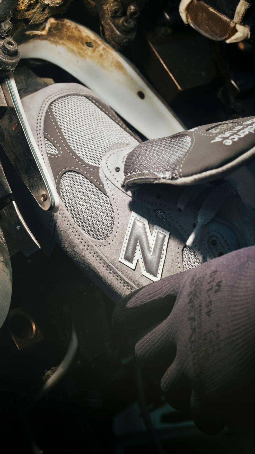 A hand putting a sneaker into a machine during its construction.