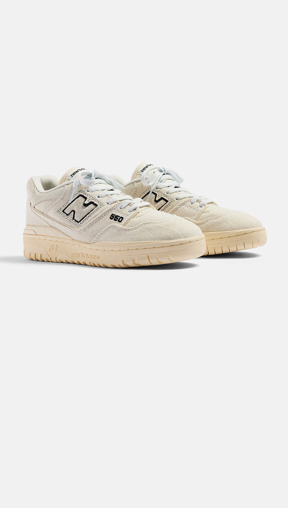 Paire de chaussures de basket-ball blanc cassé posées sur un fond gris.