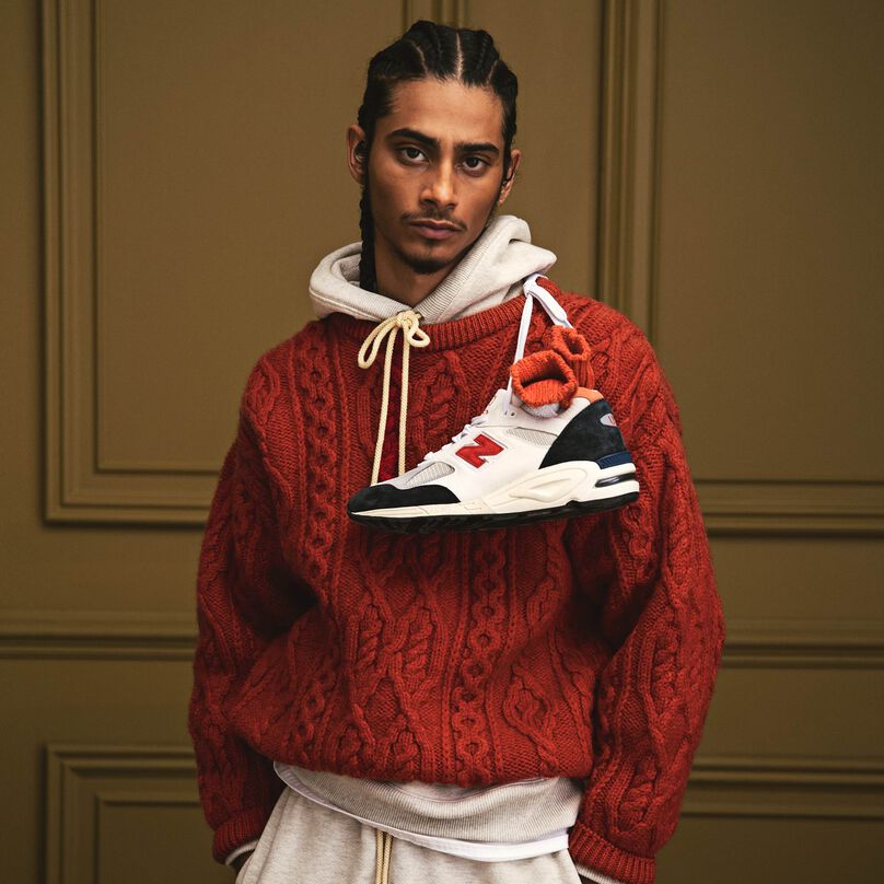 Homme portant un sweat-shirt à capuche MADE in USA sous un pull rouge.