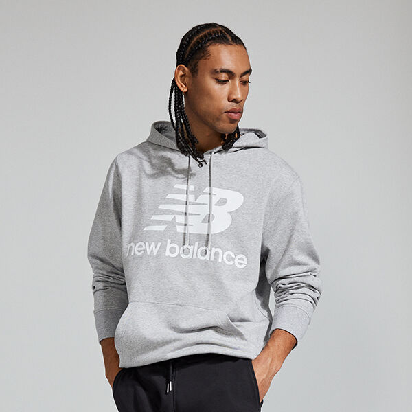 Image à partir de la taille d’un jeune homme portant un chandail à capuche NB Essentials gris chiné et un pantalon de survêtement noir 