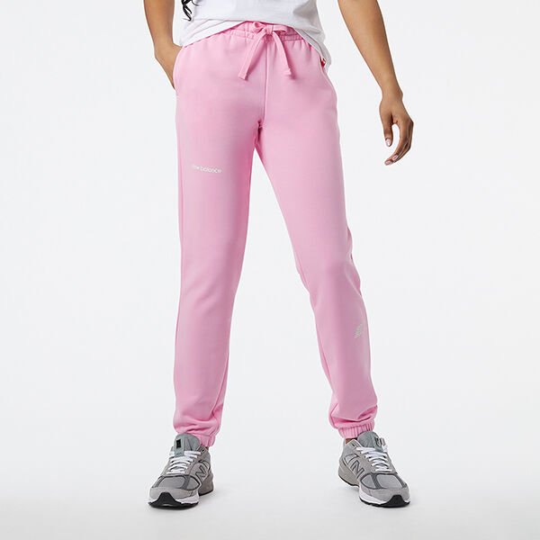 Image d'une femme de la taille vers le bas portant un pantalon de survêtement NB rose clair et des chaussures de sport NB 990v5 grises