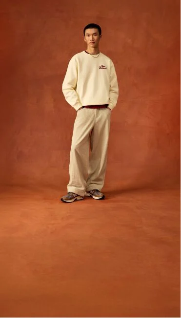 Man standing with beige sweater and hands up his pockets.