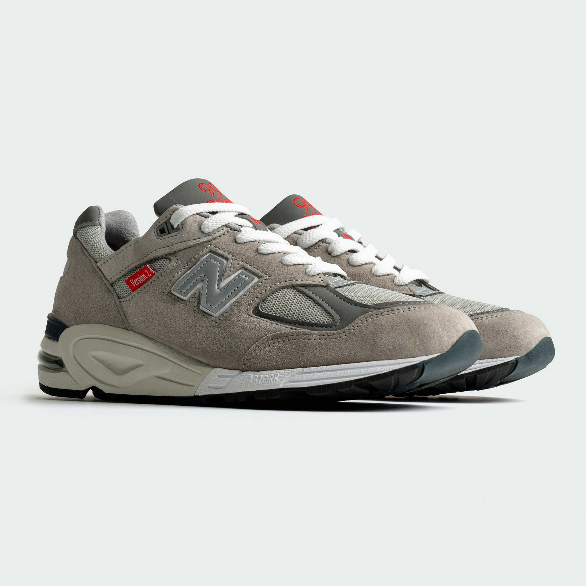 Les baskets 990v2 sur un fonds de studio gris.