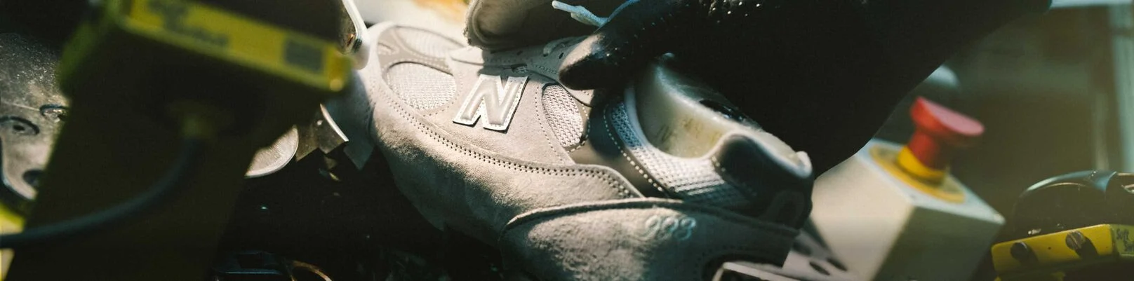 A hand putting a shoe in a device in a factory environment.