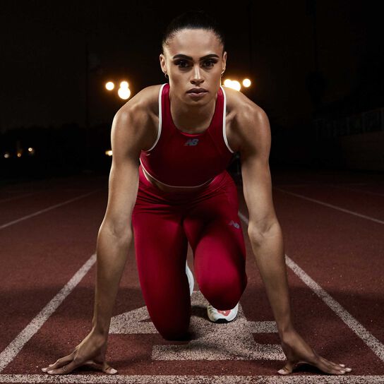 Sydney McLaughlin sur la piste la nuit, vêtue de vêtements Q Speed