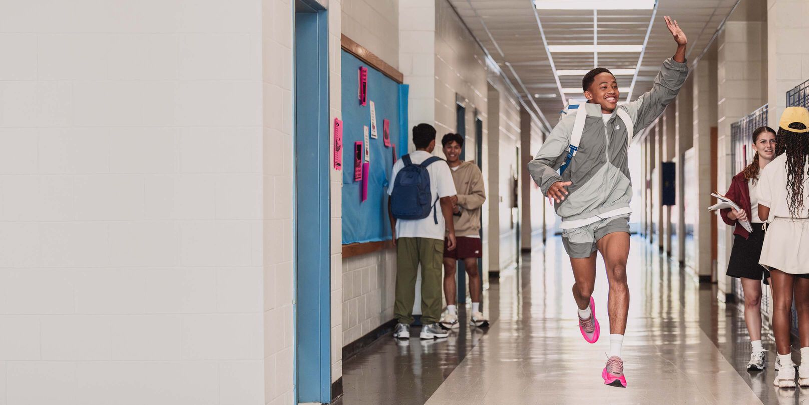Quincy Wilson wearing the FuelCell Rebel shoes running and waving at a hallway. 