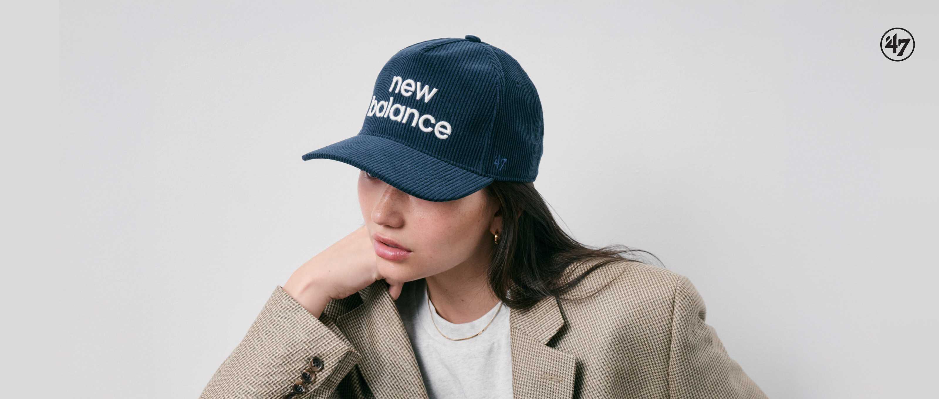 Woman wearing New Balance hat standing against white wall