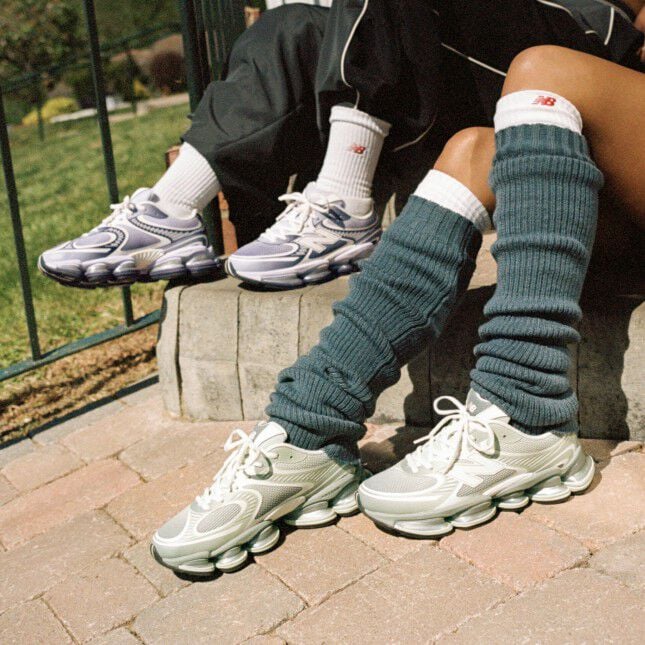Deux personnes assises sur un trottoir portant des baskets New Balance.
