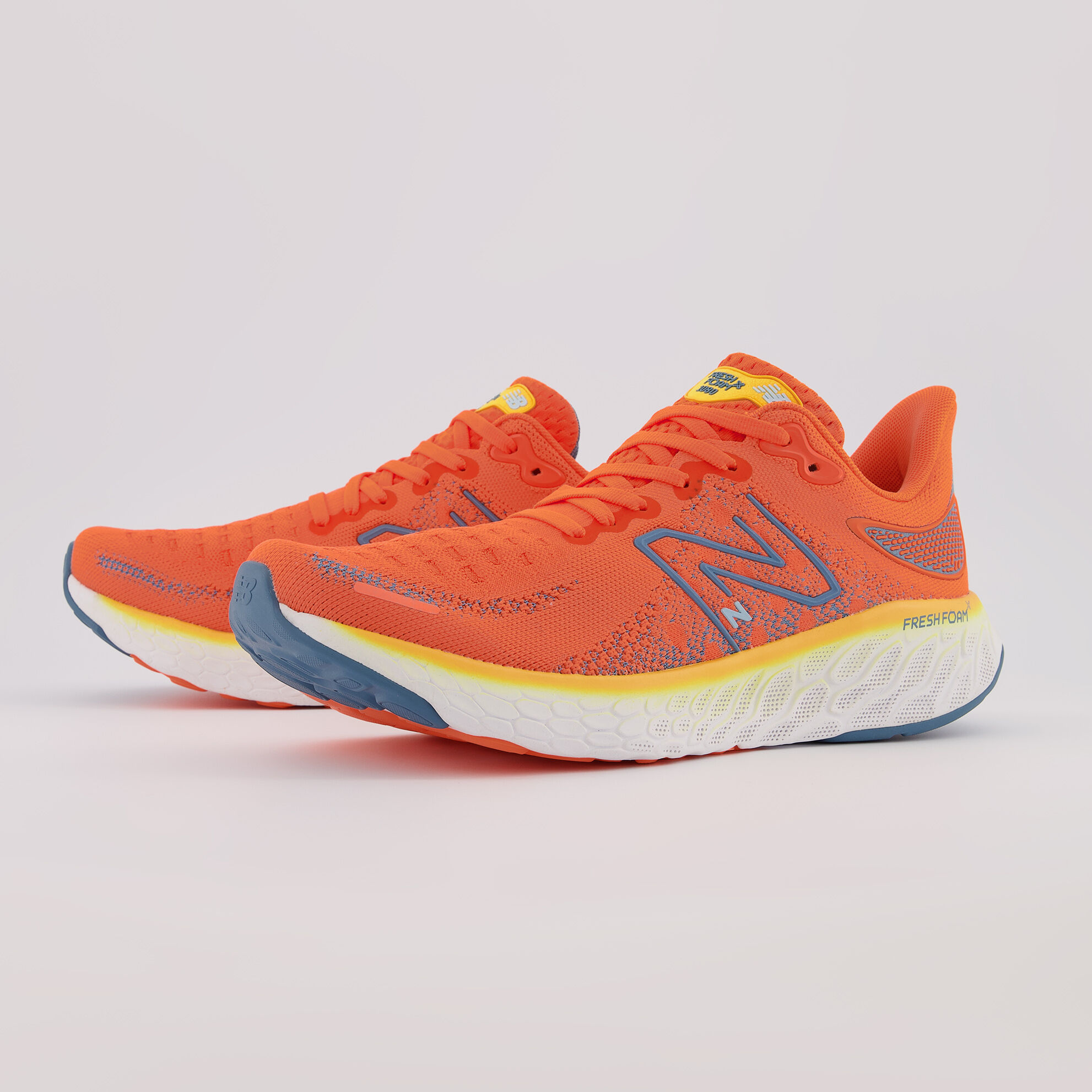 Side profile of a pair of orange Fresh Foam 1080v12 shoes on a light grey background