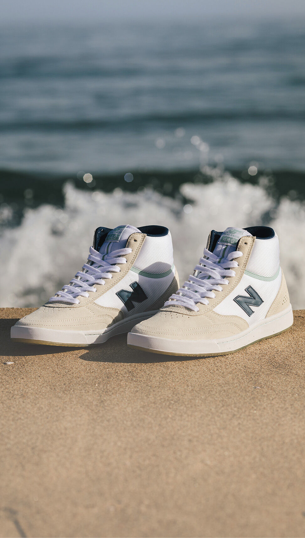 Pair of high top 440 shoes on a sandy beach.