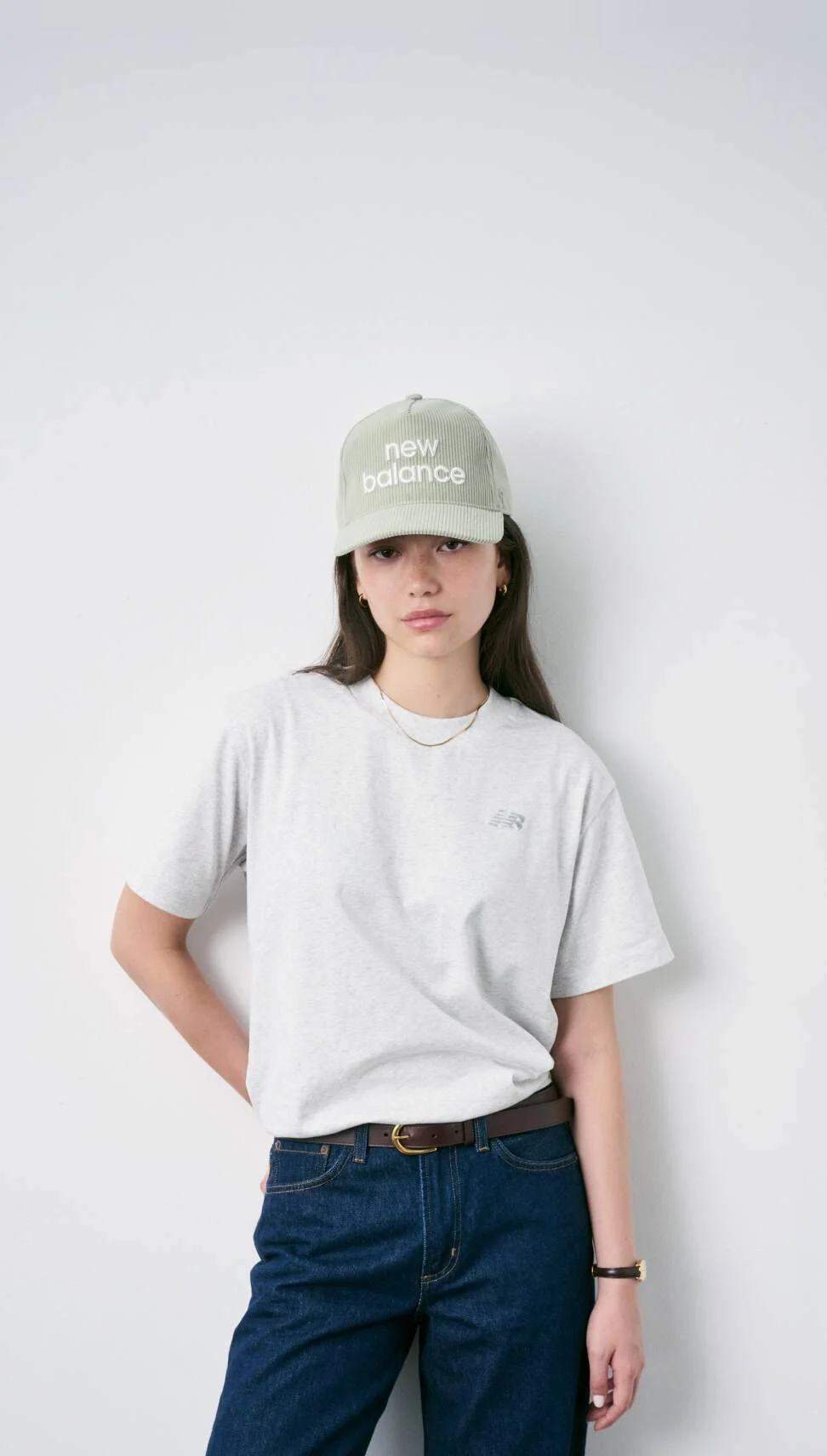 Woman wearing New Balance hat standing against white wall