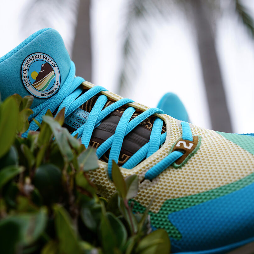 Cropped view of the front of the light blue Moreno Valley inspired KAWHI signature shoe, showing the Moreno Valley crest on the tongue and more design details on the laces and upper.