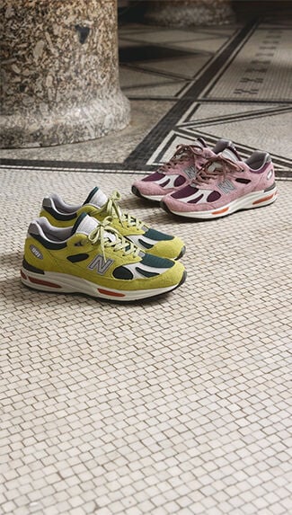 Deux paires d'espadrilles New Balance Made in UK posées sur un plancher carrelé blanc texturé.  