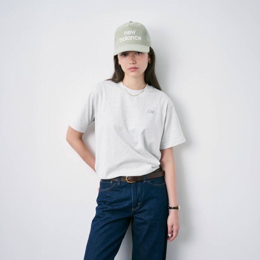 Femme assise par terre, chauss&eacute;e de New Balance et portant une casquette