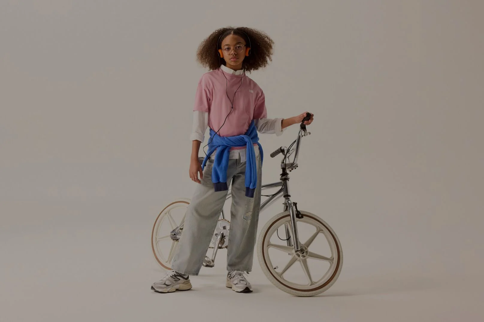 A kid in a pink shirt next to a bike.