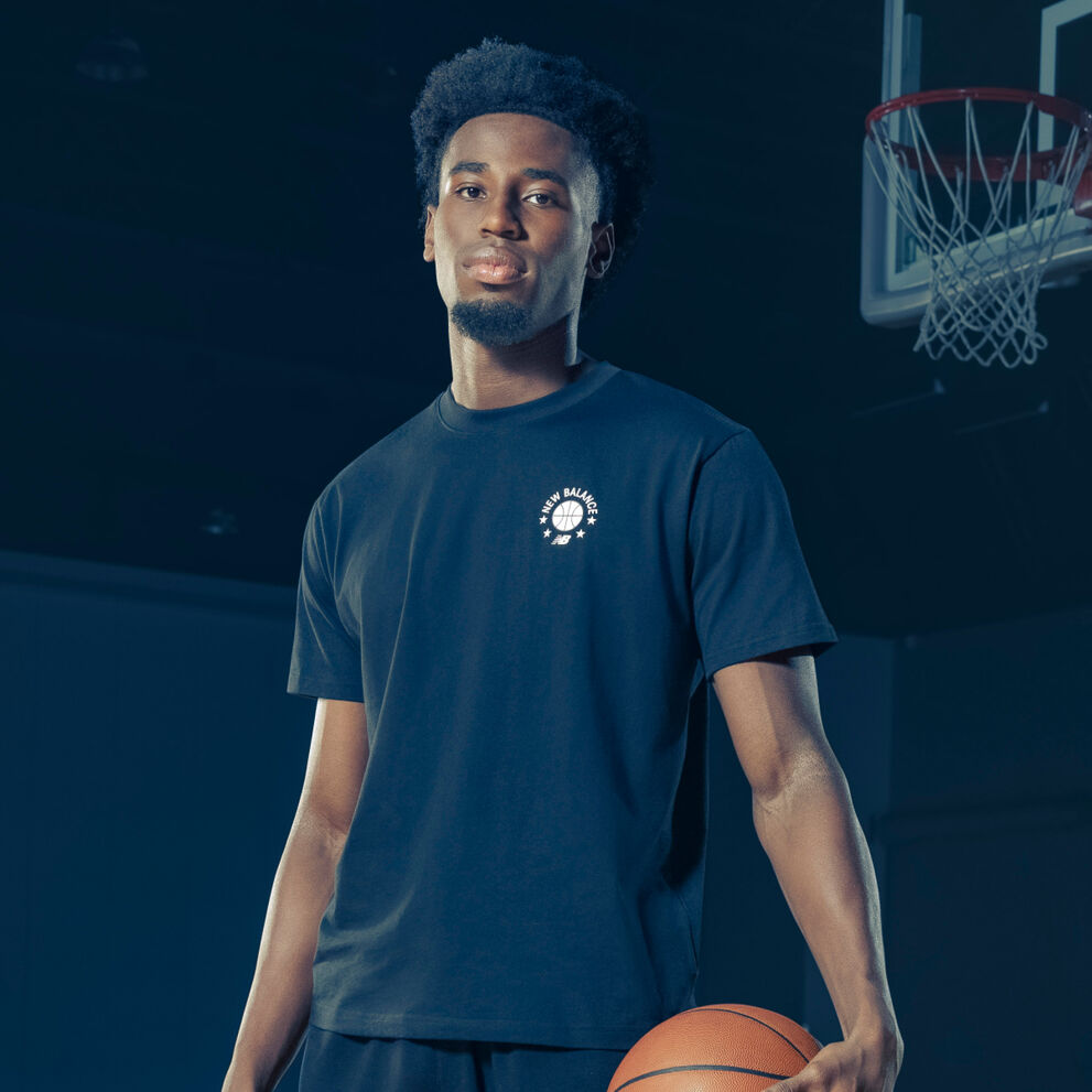 Aaron holding a ball in his left hand in a navy blue tshirt.