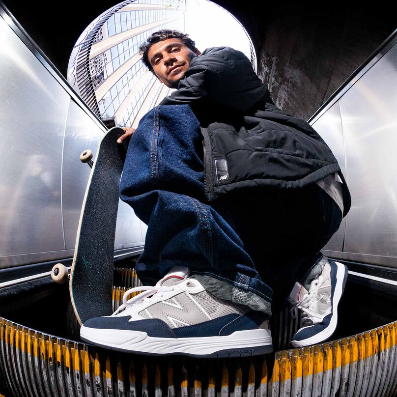 Tiago Lemos wearing 808 Numeric shoes while squatting on an escalator.