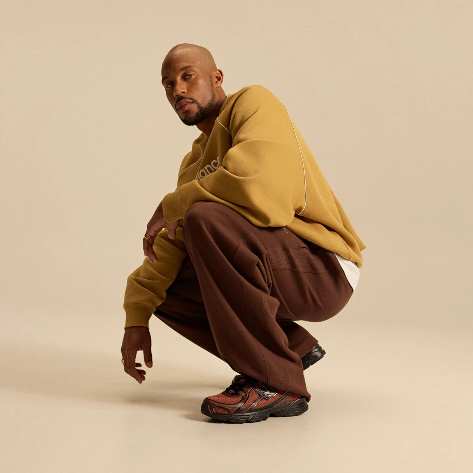 Image of Brian Reid in a New Balance outfit with a pale brown top in front of a beige background.