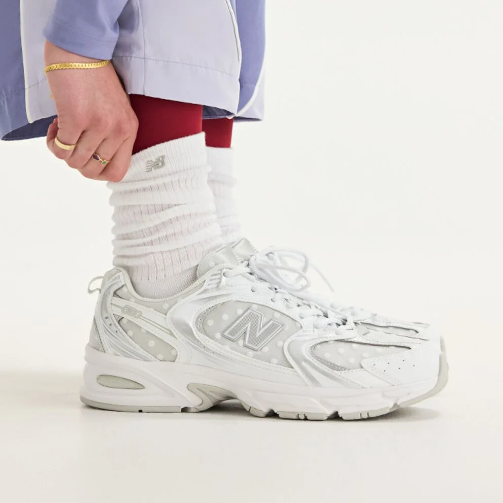 Side view of someone wearing white New Balance sneakers.