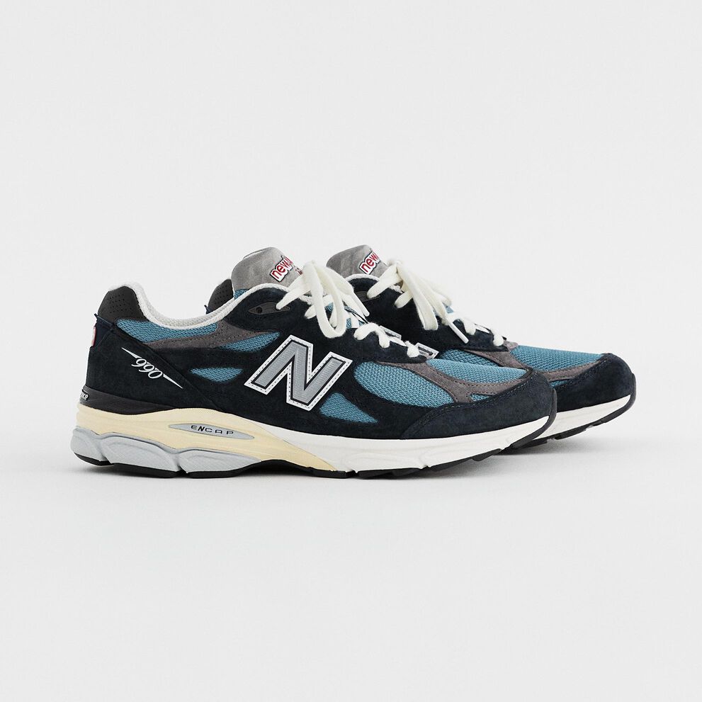 Une paire de bleu marine MADE in USA 990v3 sur fond de studio gris.