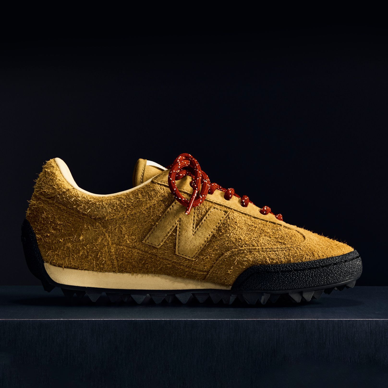 Une chaussure Gator Run en daim rose sur fond noir.