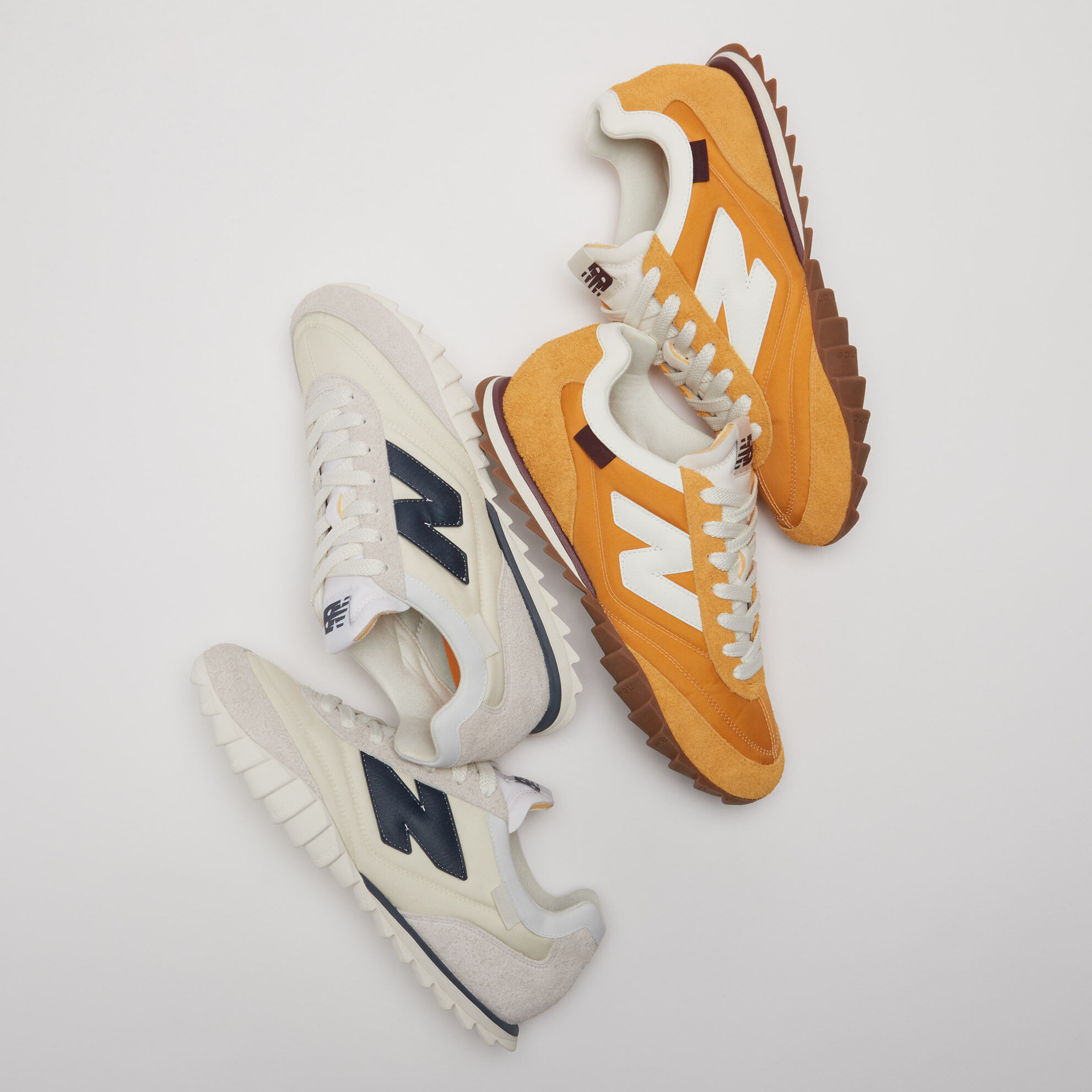 Réunion de 2 paires de RC30, une orange et une blanche, dans un décor de studio gris.