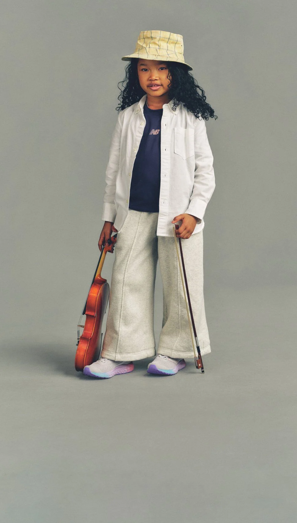 Girl wearing Fresh Foam Arishi shoes standing against a grey studio background.