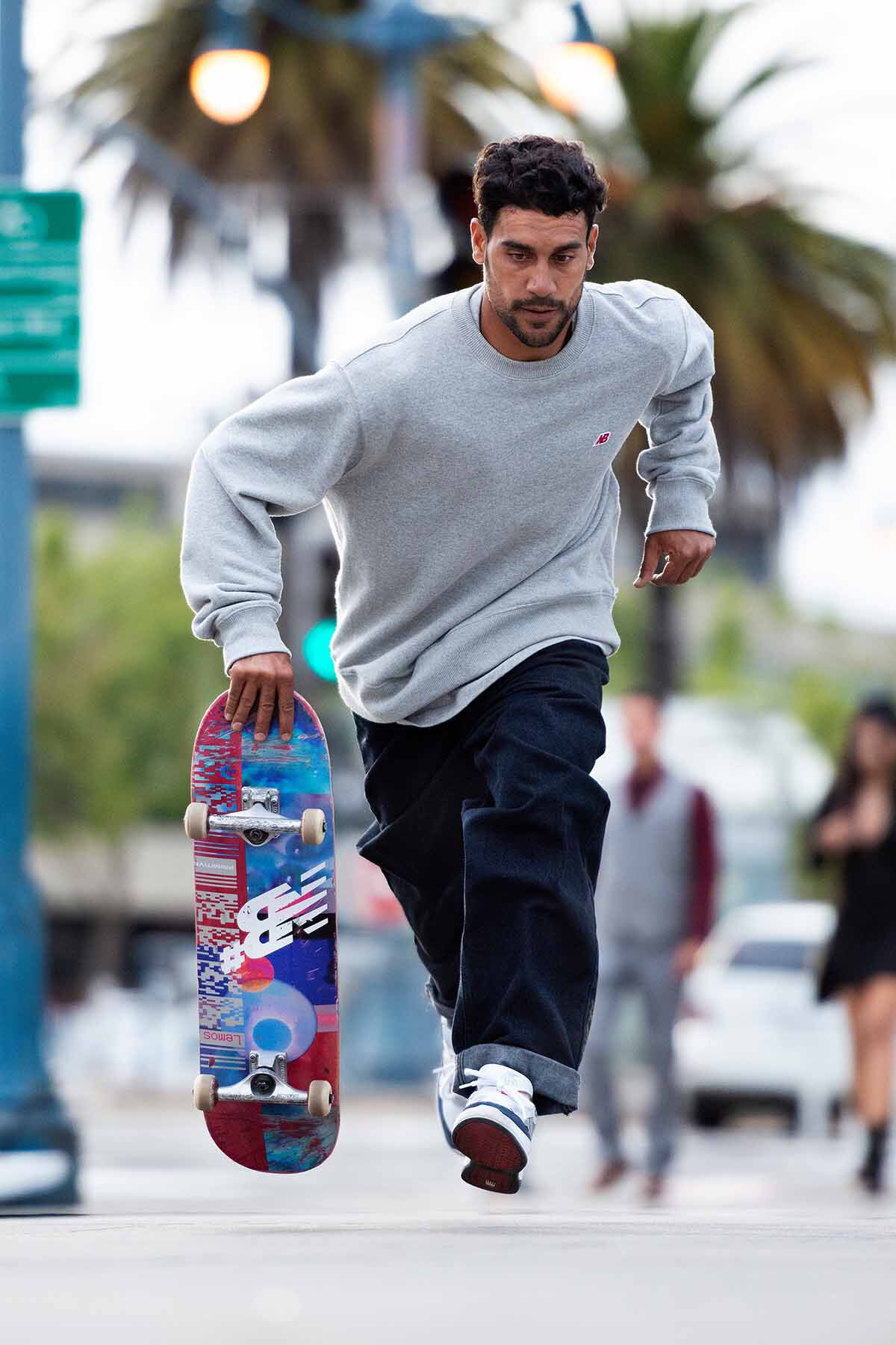 Tiago Lemos courant en tenant un skateboard dans une main.