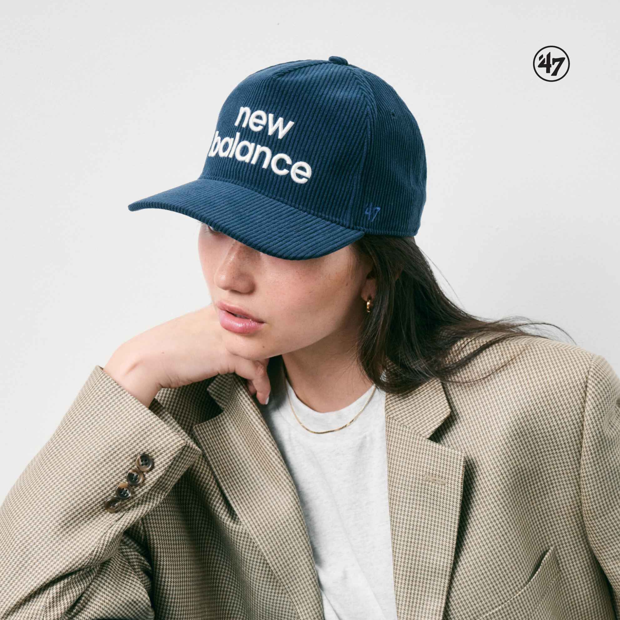 Woman wearing New Balance hat standing against white wall