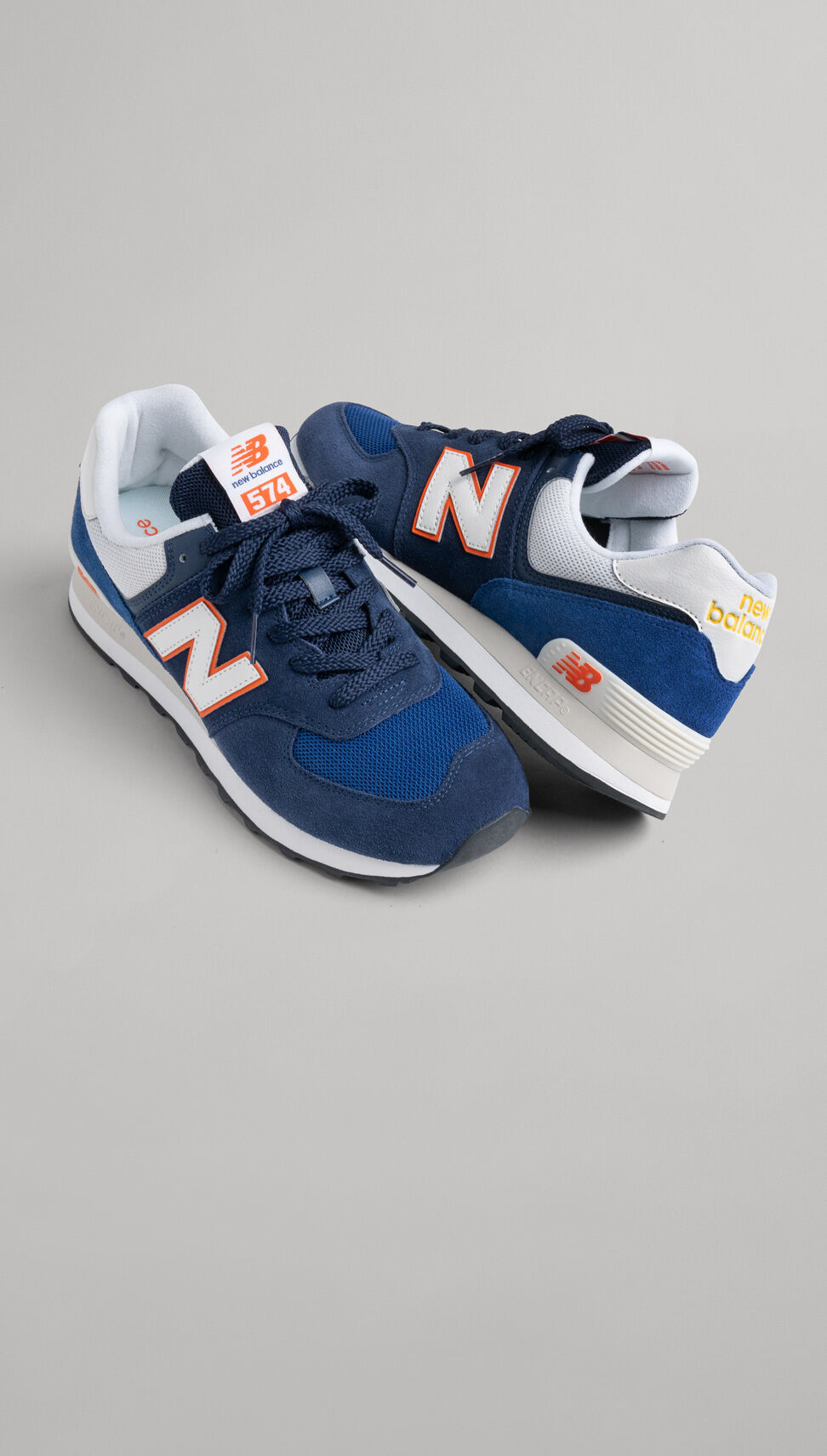 A pair of blue, orange, and white New Balance 574s. 