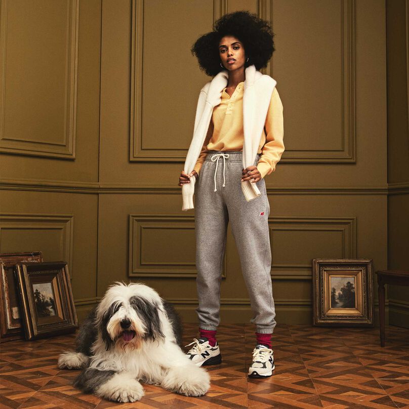 Une femme portant des vêtements et des chaussures MADE in USA, debout dans un magnifique décor intérieur, avec un chien couché près d’elle.