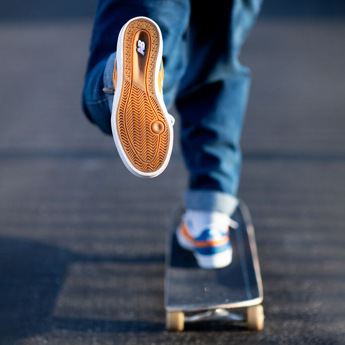 Vue de la taille d'un planchiste portant des chaussures de skate NB Numeric 272. La caméra est focalisée sur la semelle extérieure en gomme vulcanisée.