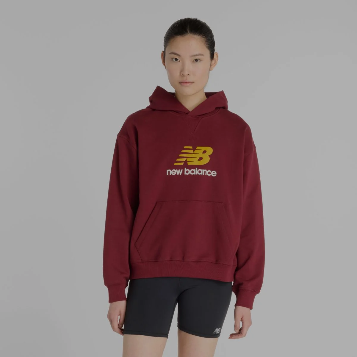 Une femme portant un hoodie rouge de New Balance.
