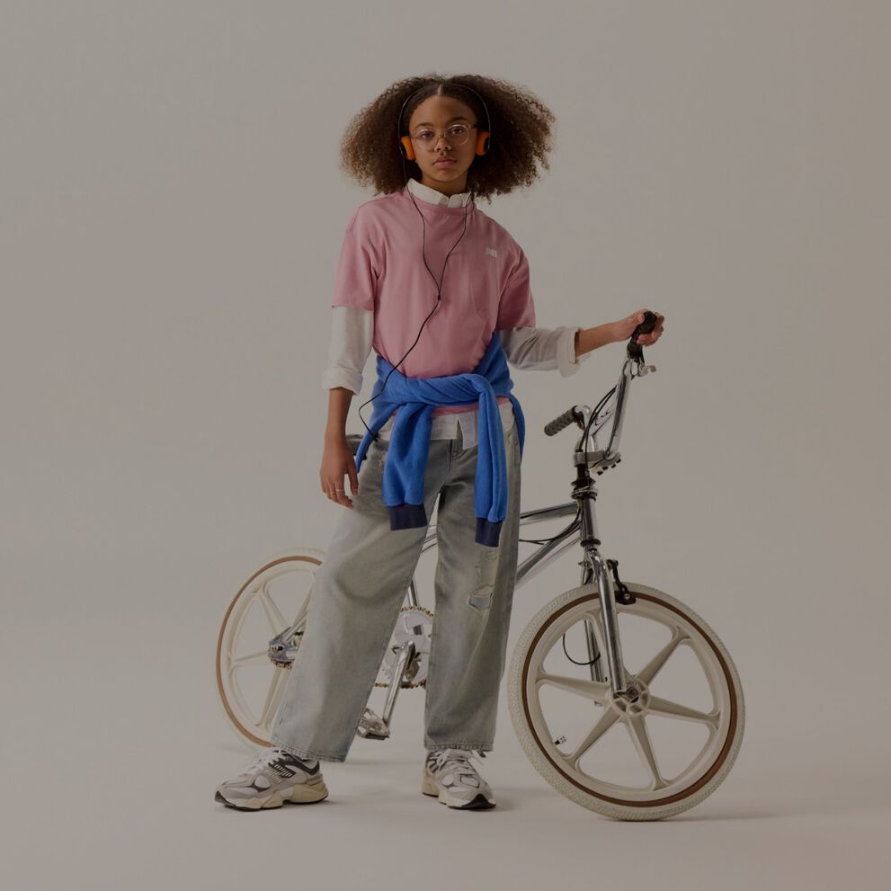 A kid in a pink shirt next to a bike.
